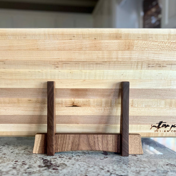 Walnut cutting board stand sitting on a maple cutting board view of back