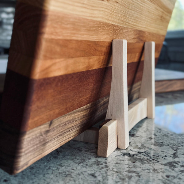 Maple cutting board stand holding an ombré cutting board view from back