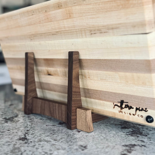 Walnut cutting board stand sitting on a maple cutting board view from back